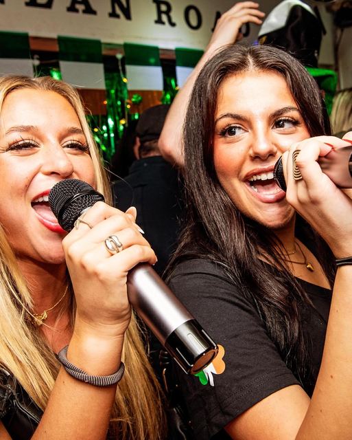 Two friends singing into a microphone
