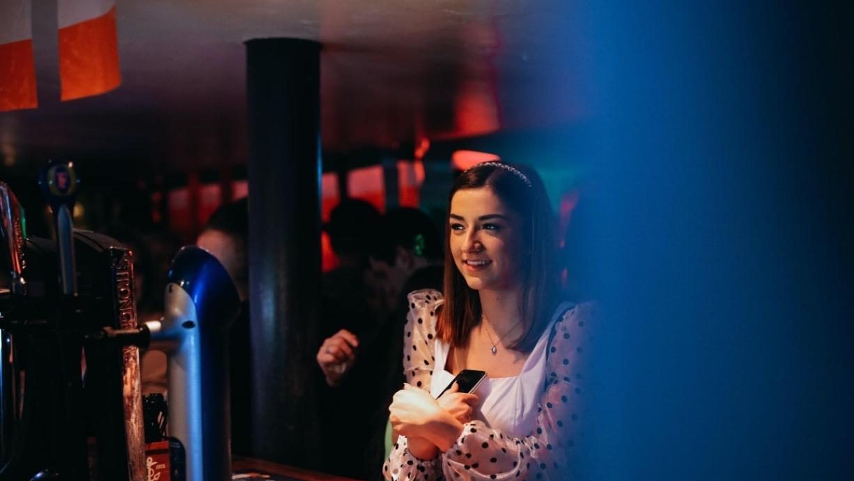A guest smiling at the bar by the Guinness taps